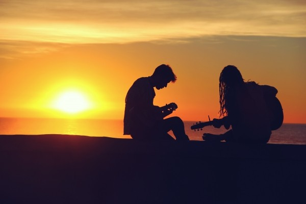 silhouette-of-young-couple-playing-guitar-at-sunset